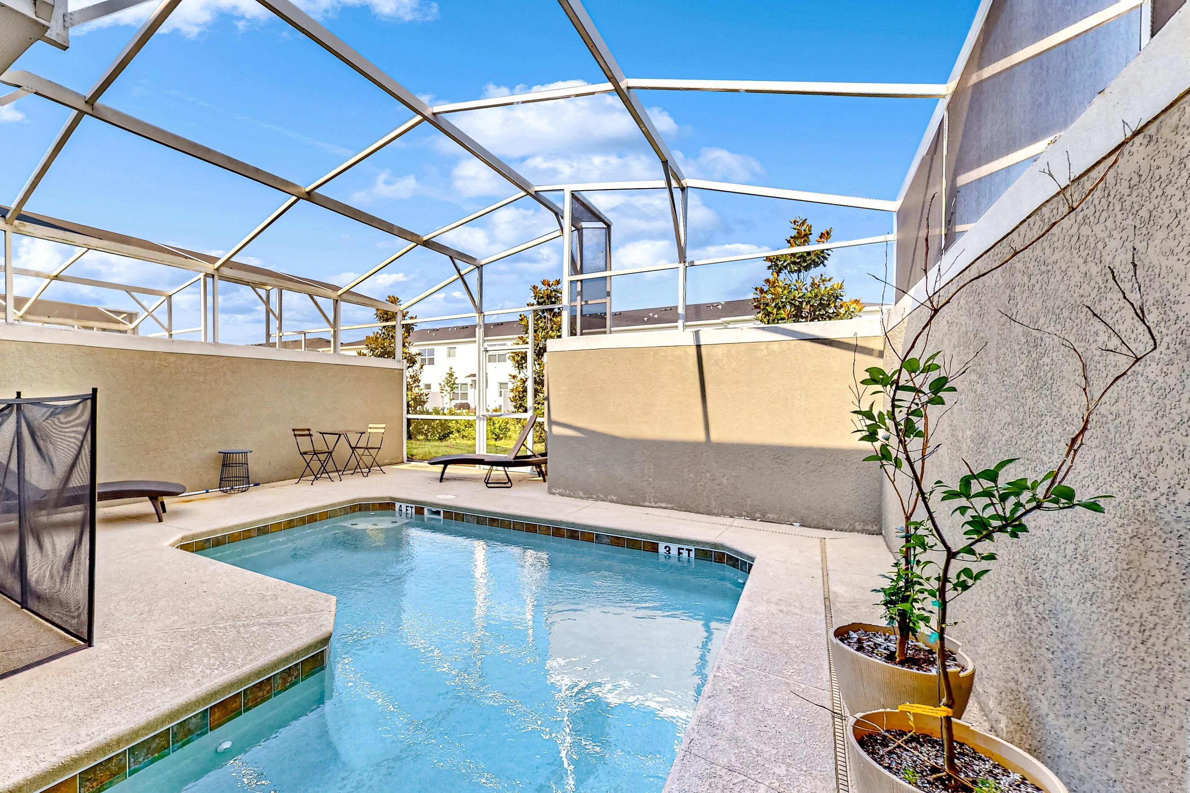 Una piscina con cerramiento de vidrio, rodeada por una terraza de concreto y plantas en macetas.