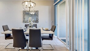 Uma área de refeições com uma mesa posta para quatro pessoas, um candelabro e um espelho na parede.