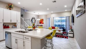 A modern kitchen with a central island, a dining area with yellow chairs, and a large window with a view. - Family-friendly Home With Private Pool, Wifi, Central AC, & Private Washer/dryer (Davenport)