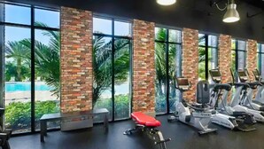 A gym with exercise equipment, large windows, and a view of a pool. - Family-friendly Home With Private Pool, Wifi, Central AC, & Private Washer/dryer (Davenport)