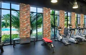 A gym with exercise equipment, large windows, and a view of a pool. - Family-friendly Home With Private Pool, Wifi, Central AC, & Private Washer/dryer (Davenport)