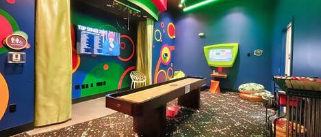 Una mesa de billar, una pantalla de televisión y una pared con diseños circulares de colores.