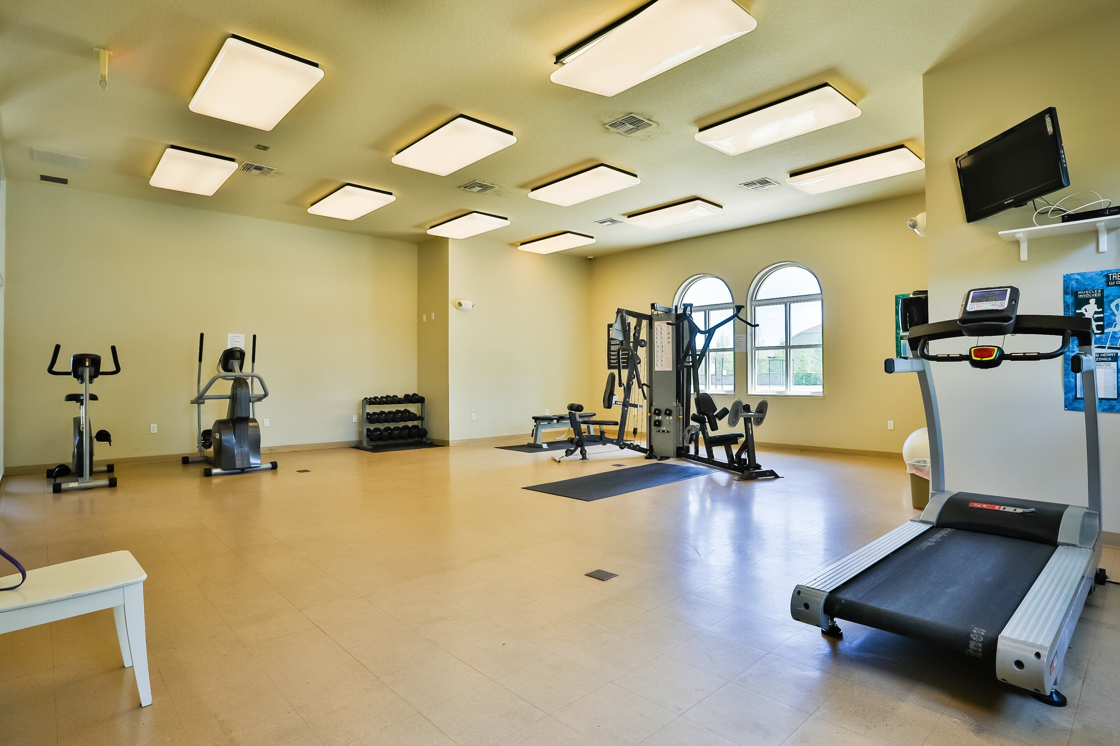 Ein geräumiges Fitnessstudio mit Laufband, Crosstrainer und Kraftgeräten.
