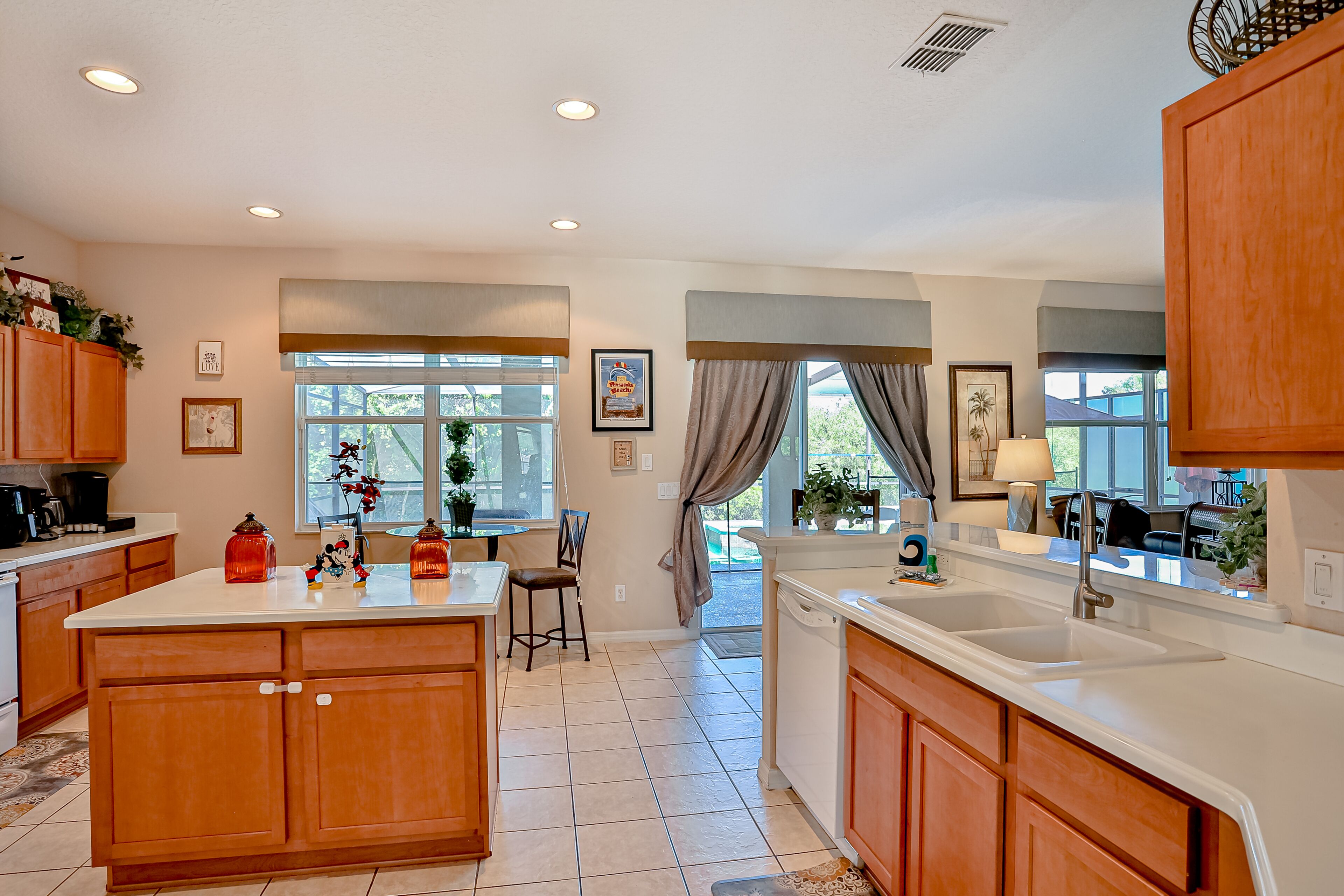 A modern kitchen with wooden cabinets, a large island, and a view to the outside.