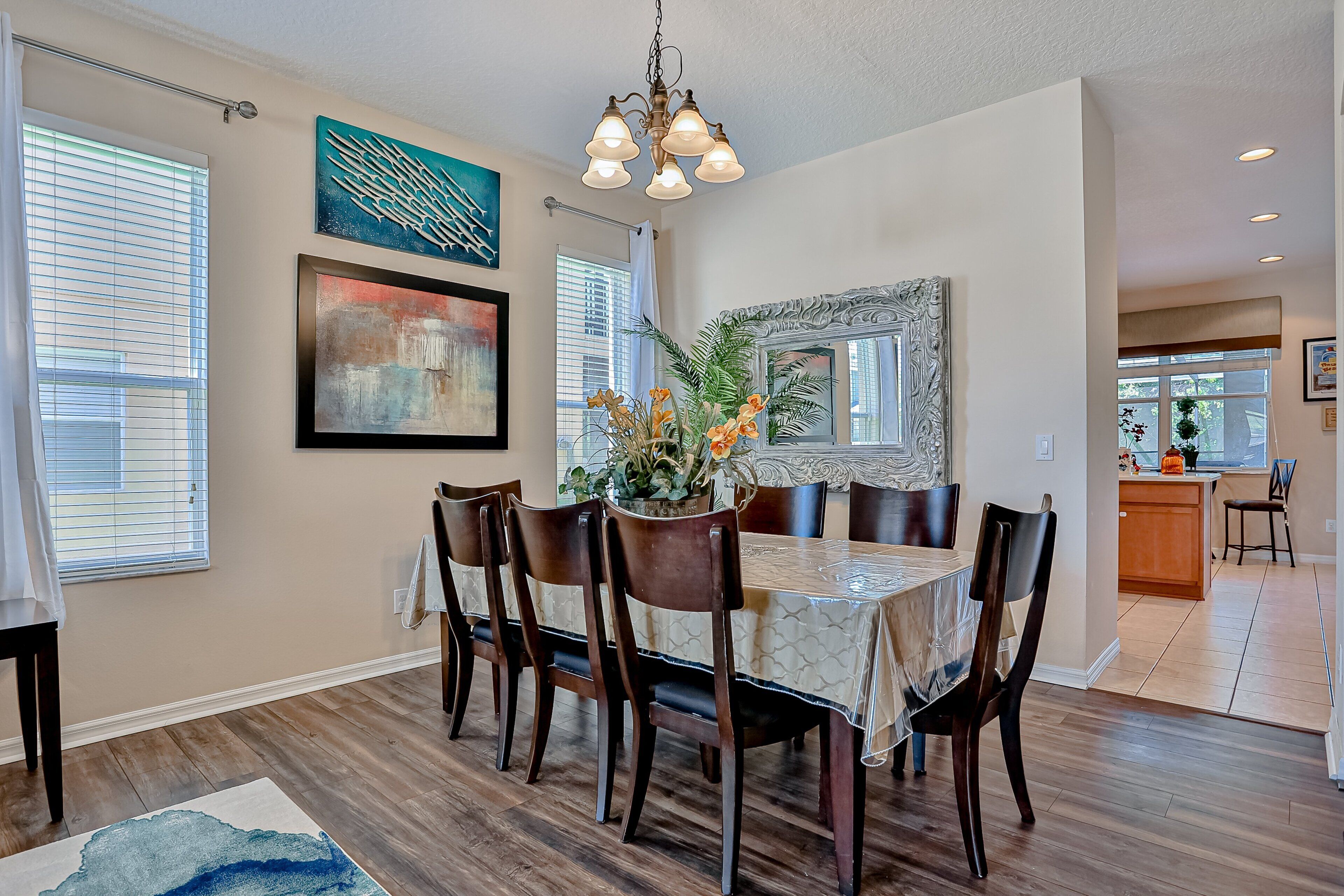 A dining area with a round table, chairs, a chandelier, and artwork on the walls.