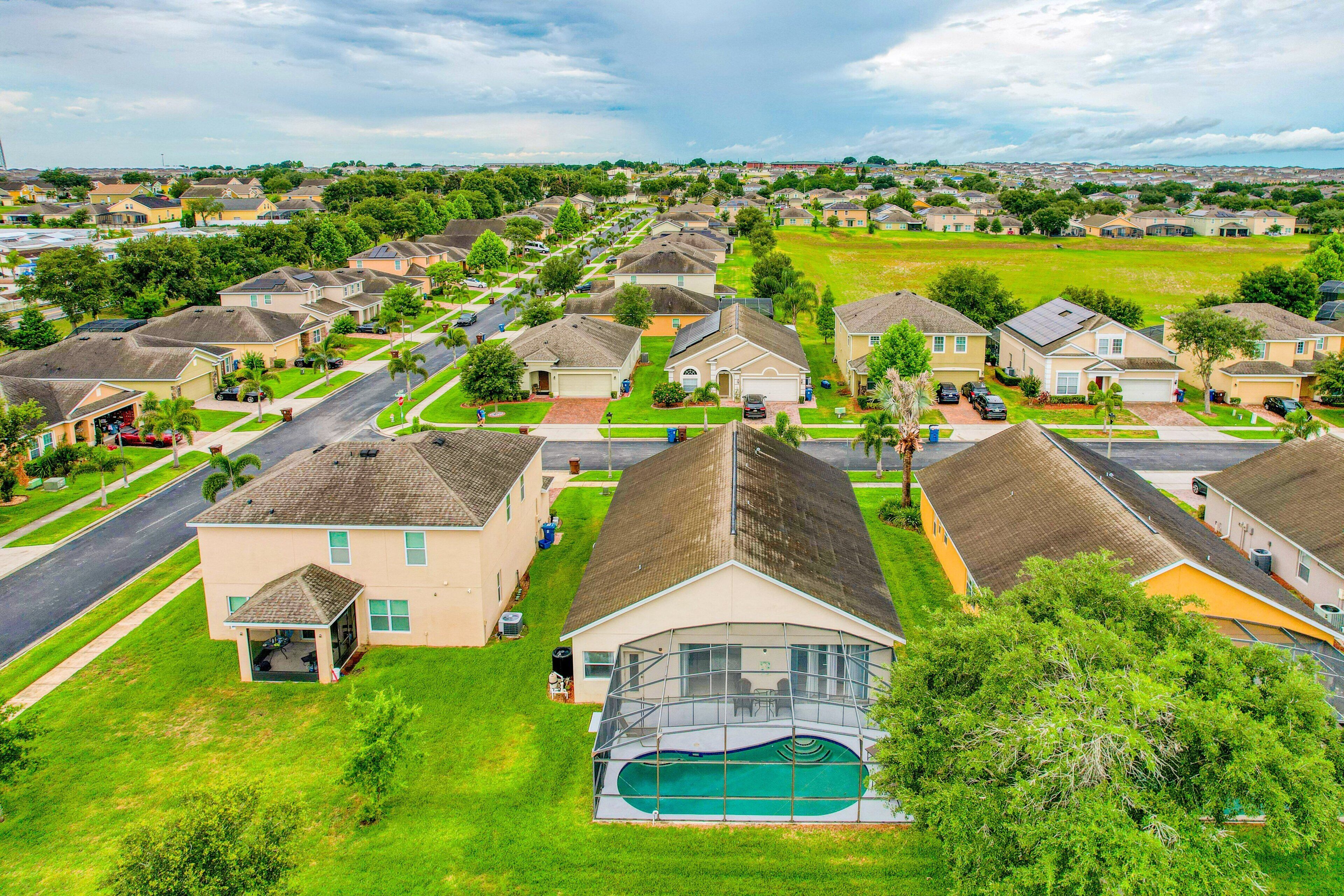 A residential neighborhood with houses, a swimming pool, and a road.