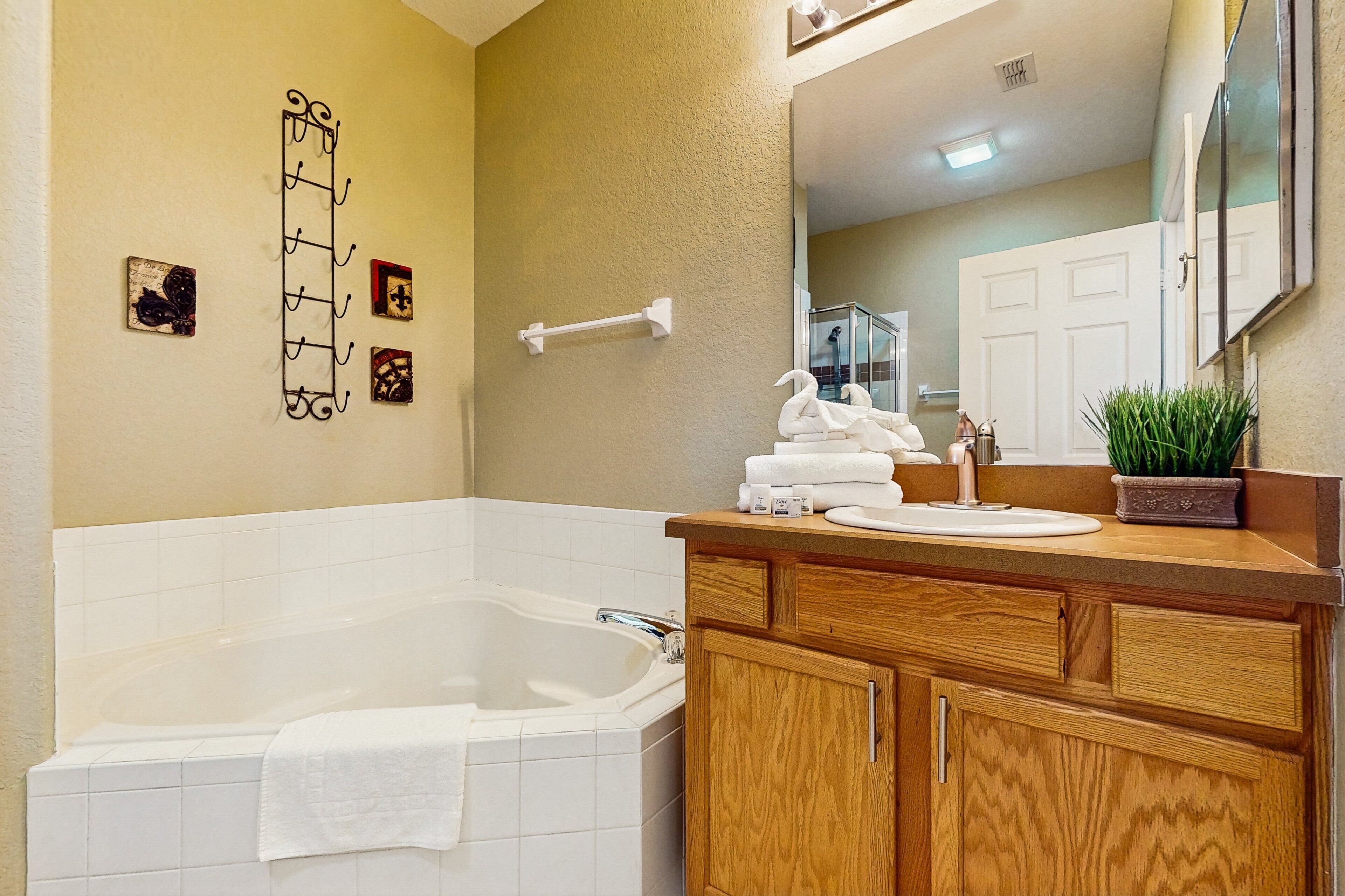 A bathroom with a bathtub, wooden vanity, and a mirror.