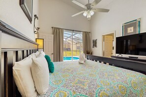A bedroom with a large bed, a ceiling fan, a TV, and a view of a swimming pool. - Home in Gated Community W/private Heated Pool, air Hockey, Tennis, Clubhouse (Davenport)