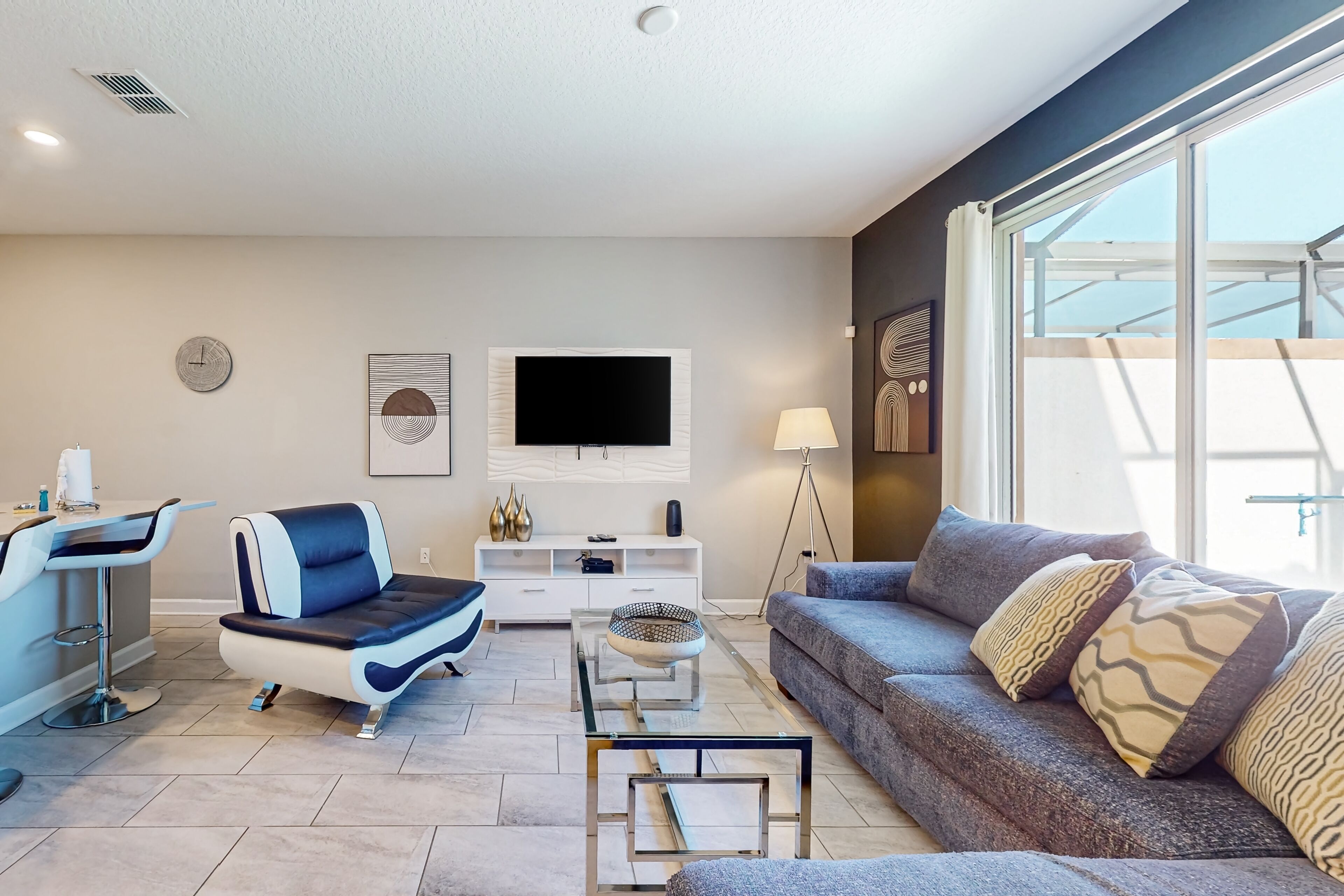 Un salon moderne comprenant un canapé, une table basse, un téléviseur et un coin repas avec une chaise et une table.