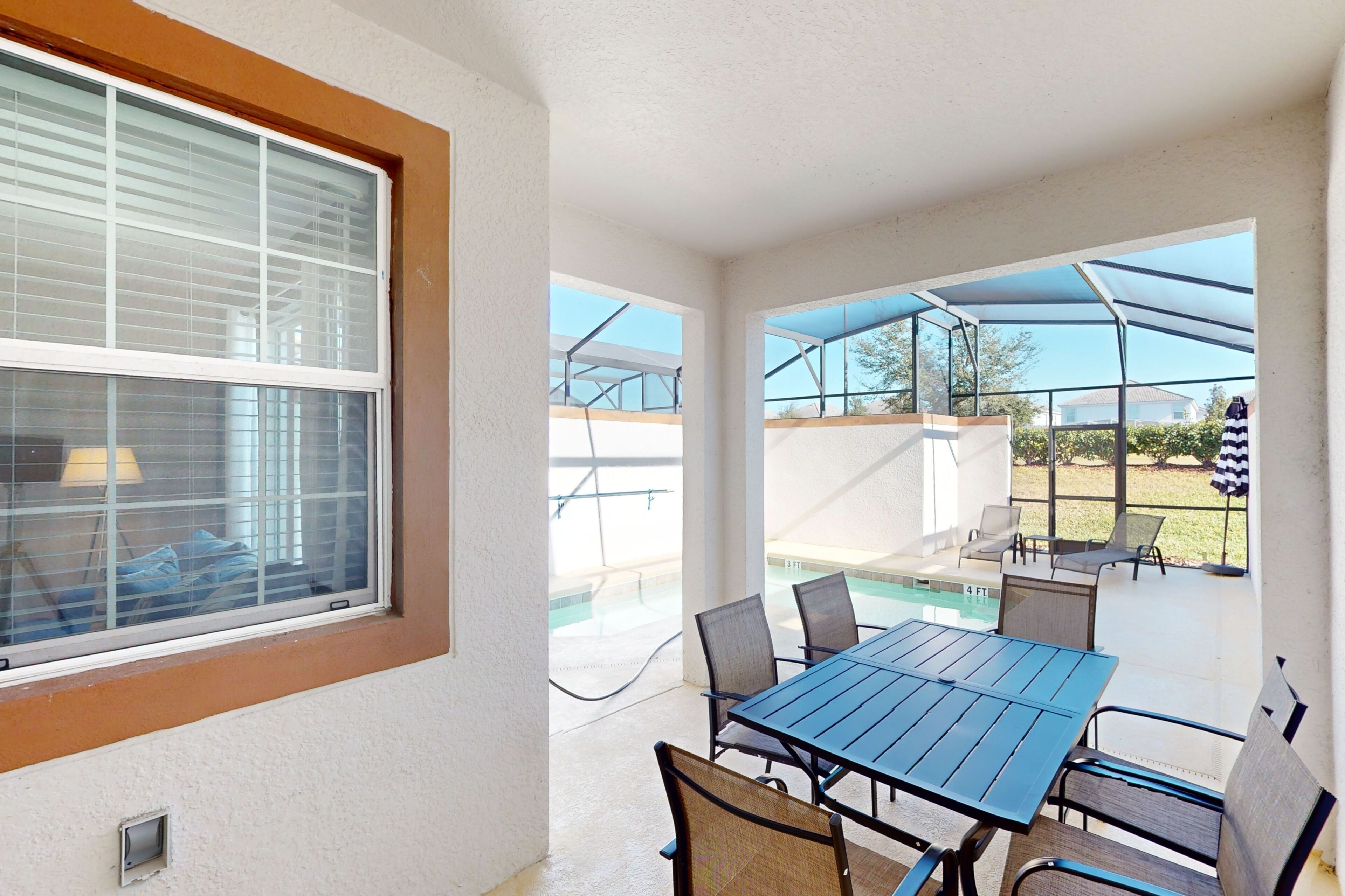 An outdoor patio with a table and chairs, a pool, and a covered area with umbrellas.