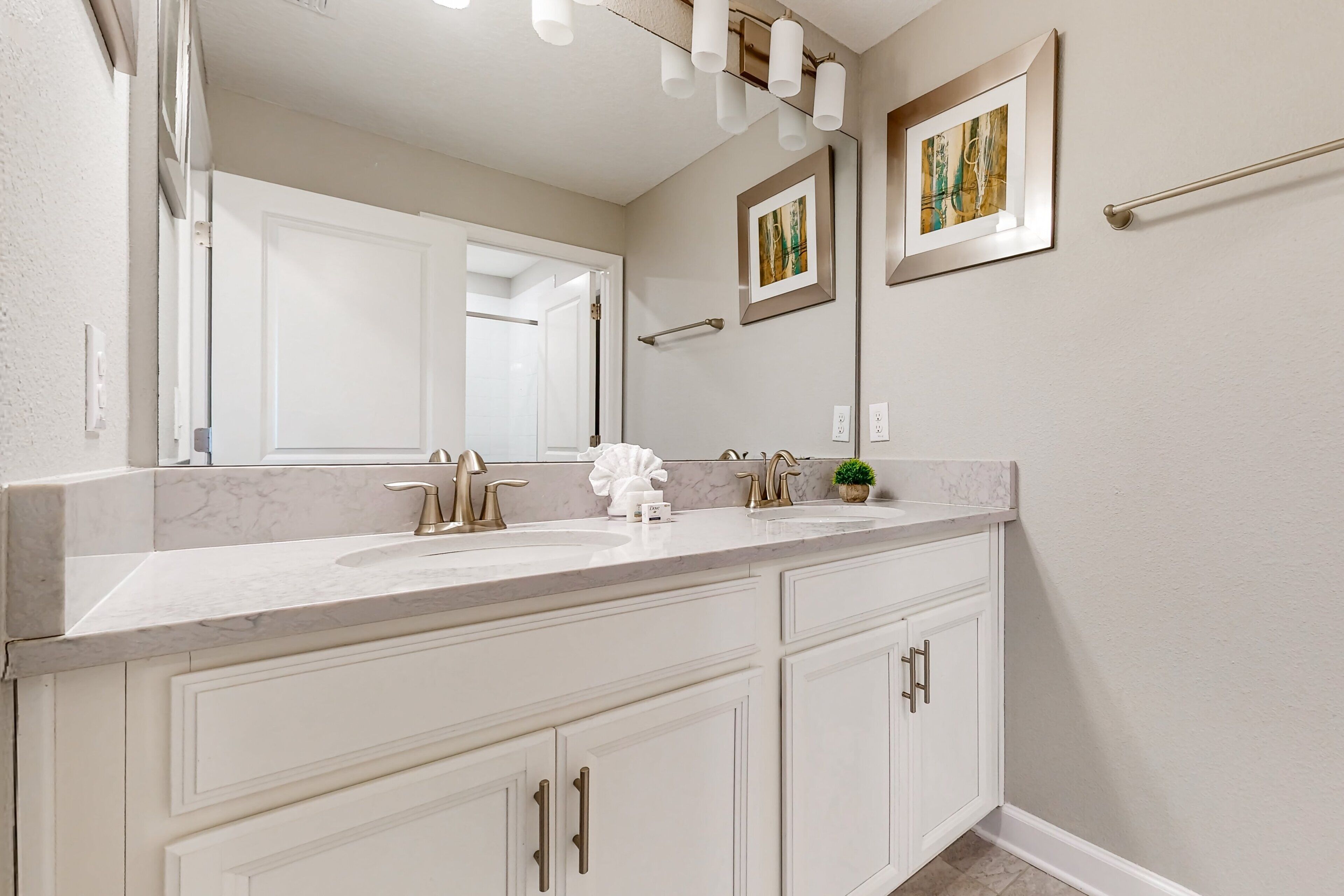 A bathroom with a double sink, a large mirror, and a towel rack.