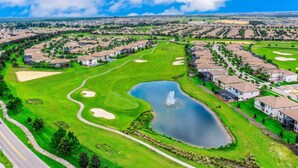 Un parcours de golf avec un étang, entouré de bâtiments résidentiels.