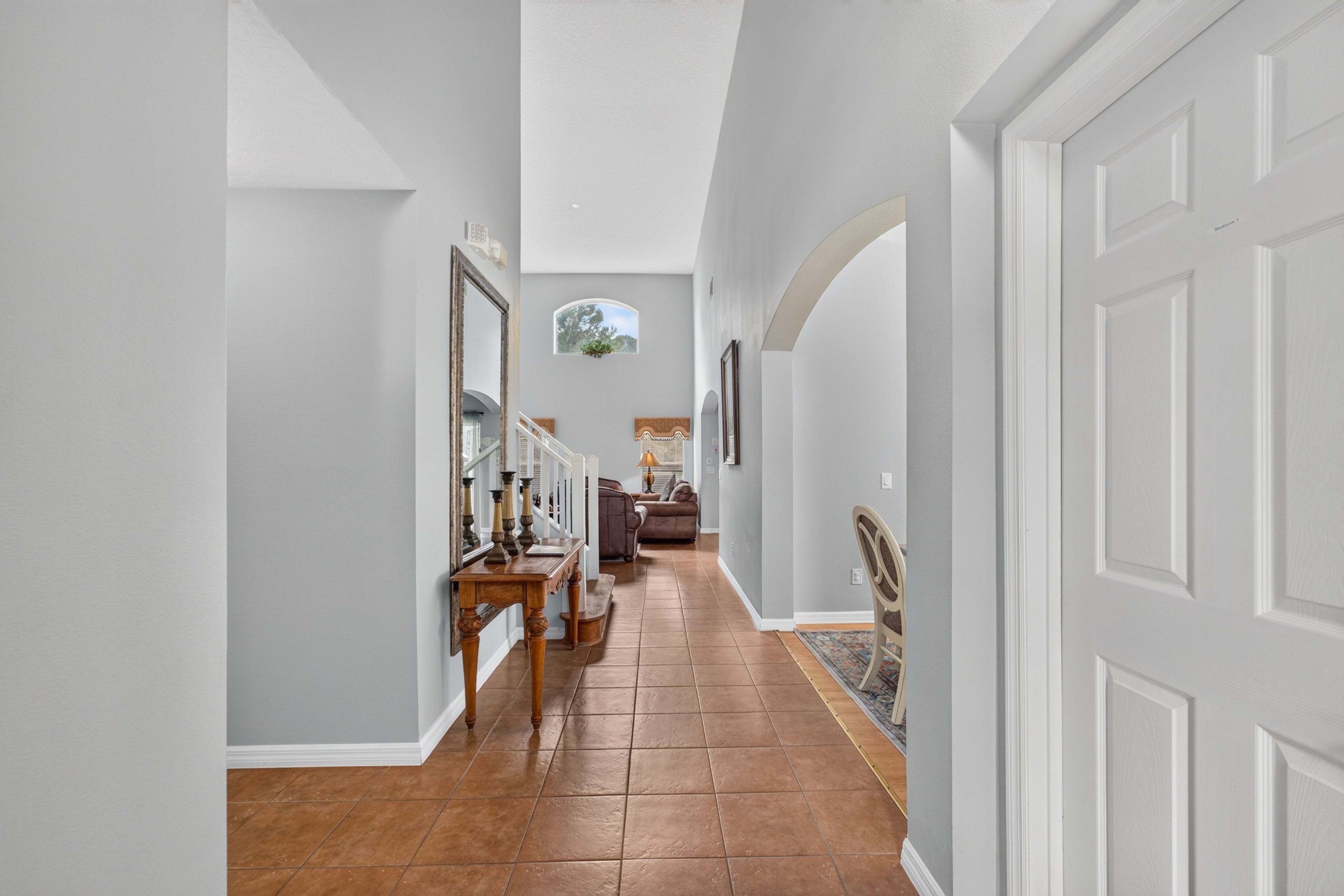 A hallway with a wooden floor, white walls, and a door on the right.