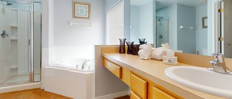 A bathroom with a shower, bathtub, vanity with sink, and a large mirror.