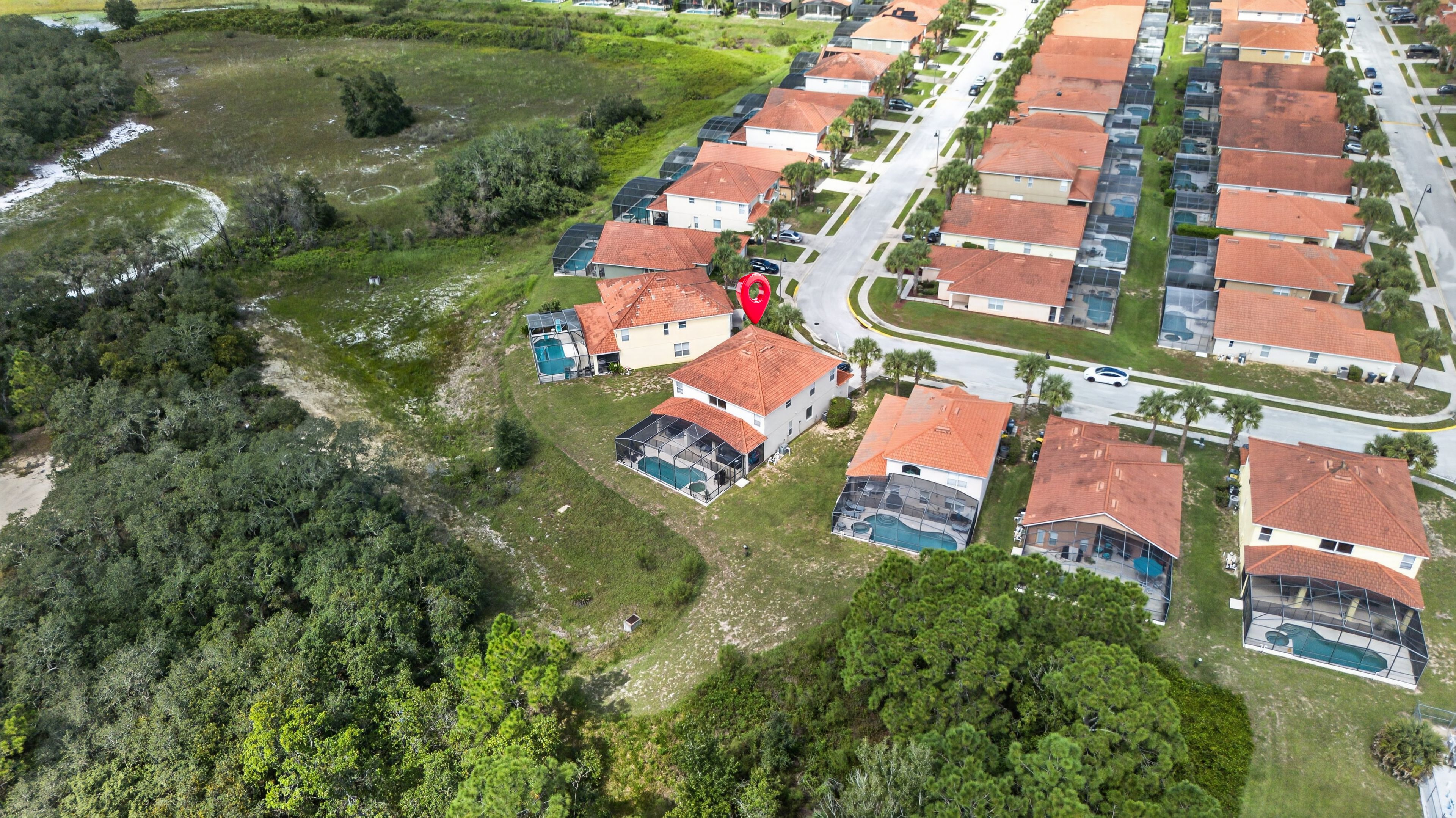 Vista aérea de un barrio residencial con casas, una piscina y un marcador rojo que indica una ubicación específica.