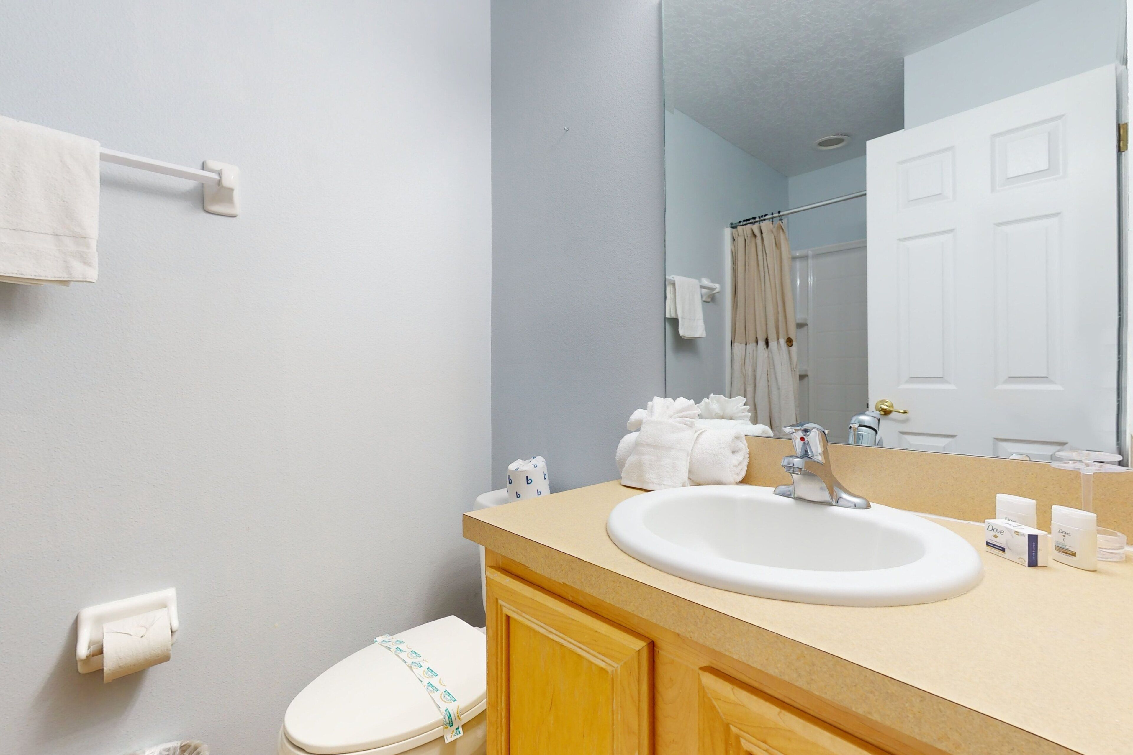 Une salle de bain avec un lavabo blanc, un miroir et des toilettes.