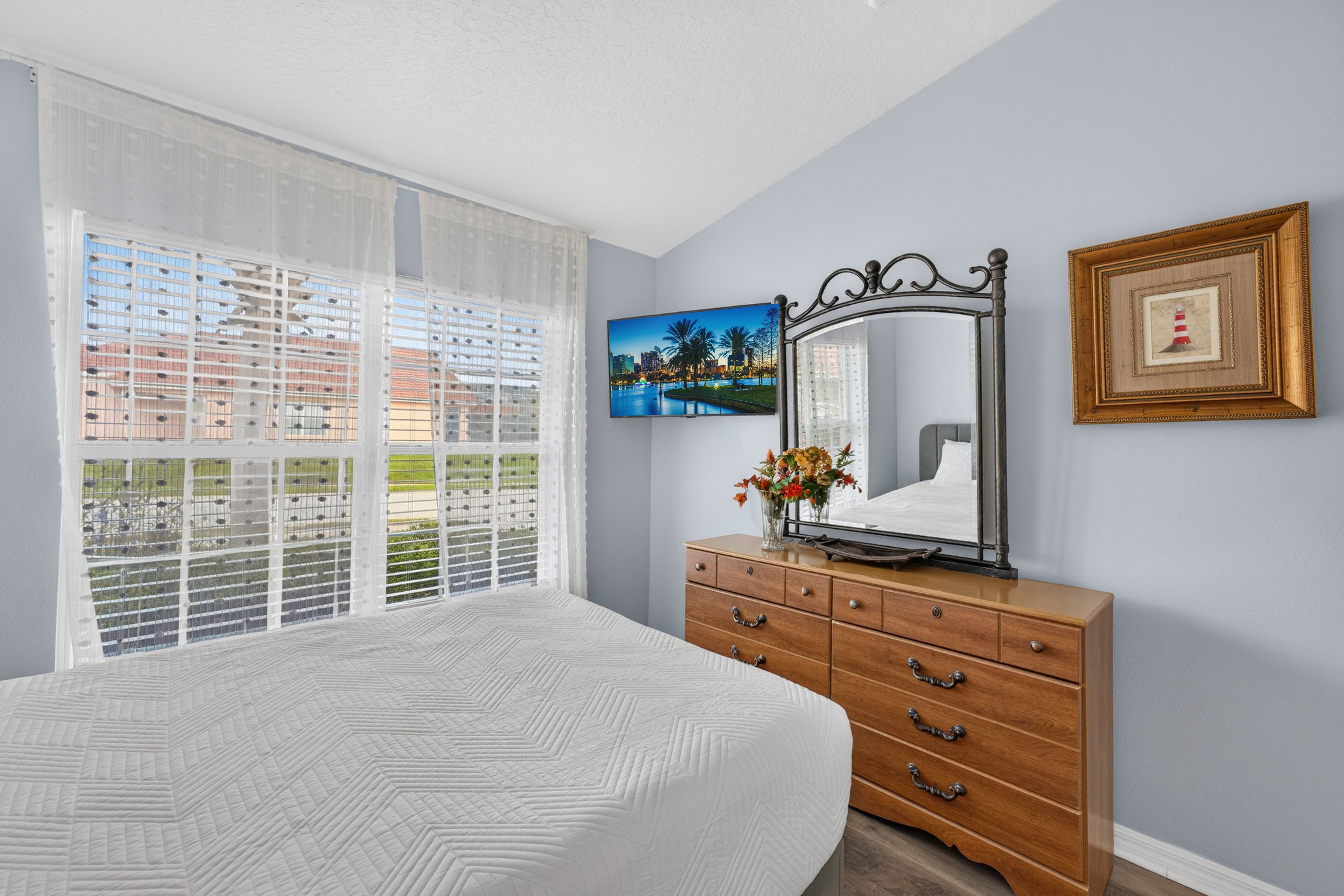 Un dormitorio con cama, cómoda, espejo y ventana con persianas.