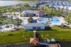 A resort with multiple buildings, a central pool, and a dock with surfboards. - Modern Townhouse With Private Pool, Resort Amenities, Themed Rooms and More (Kissimmee)