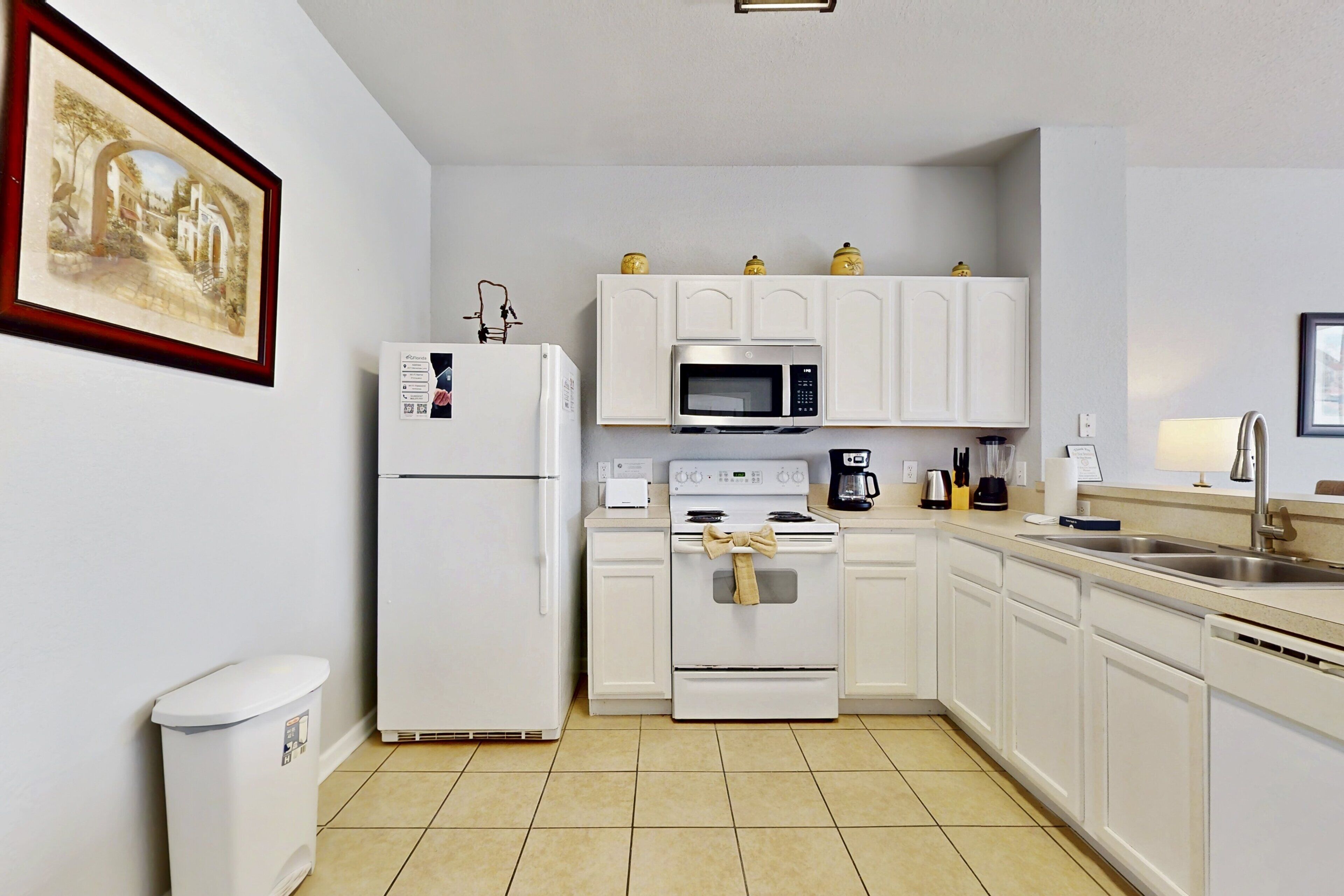 A kitchen with white cabinets, a refrigerator, a microwave, an oven, and a sink.