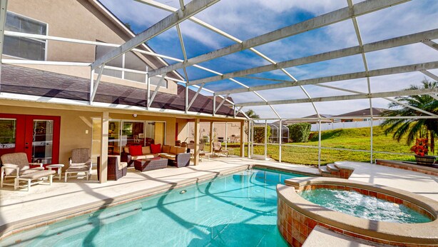 Ein Poolbereich mit Whirlpool, Liegestühlen und einer überdachten Terrasse.