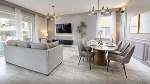 Una sala de estar moderna con sofá, mesa de comedor, sillas y televisor.