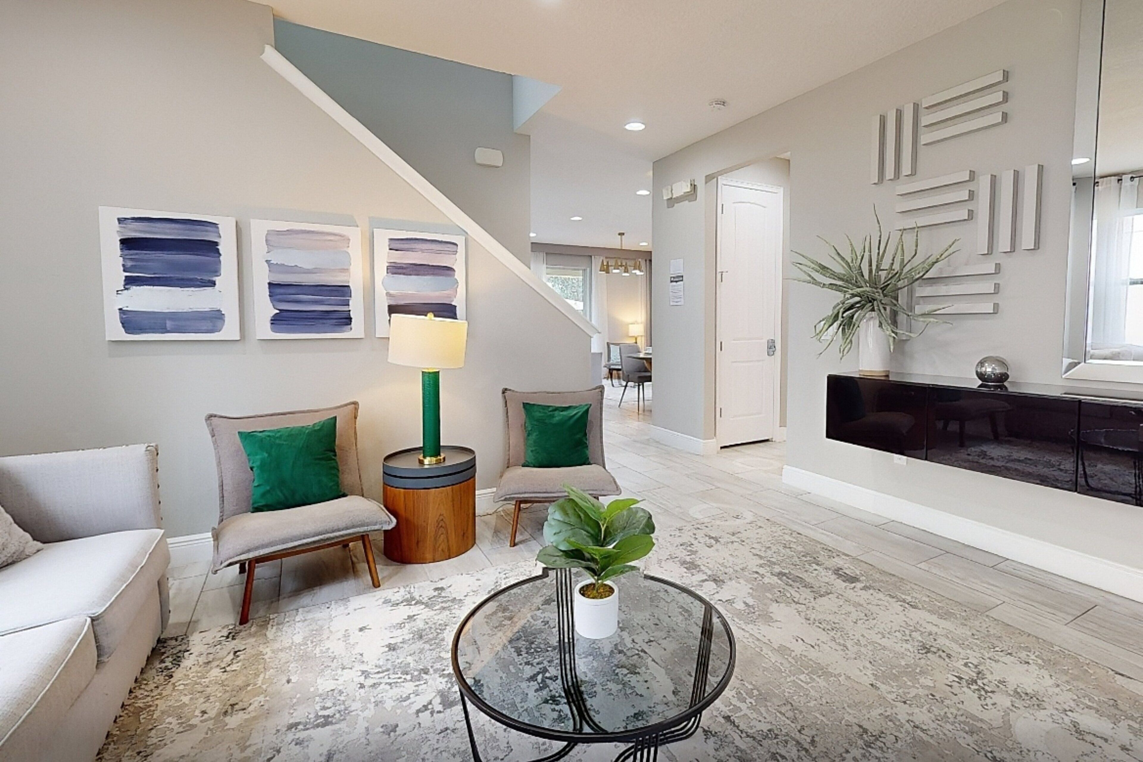 A modern living room with a sofa, chairs, a coffee table, and abstract art on the wall.