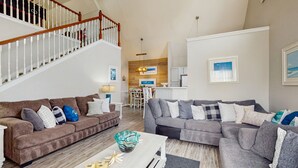 A spacious living room with two sofas, a coffee table, and a staircase. - Spacious Condo With Themed Rooms, Foosball Table and Shared Pool (Kissimmee)
