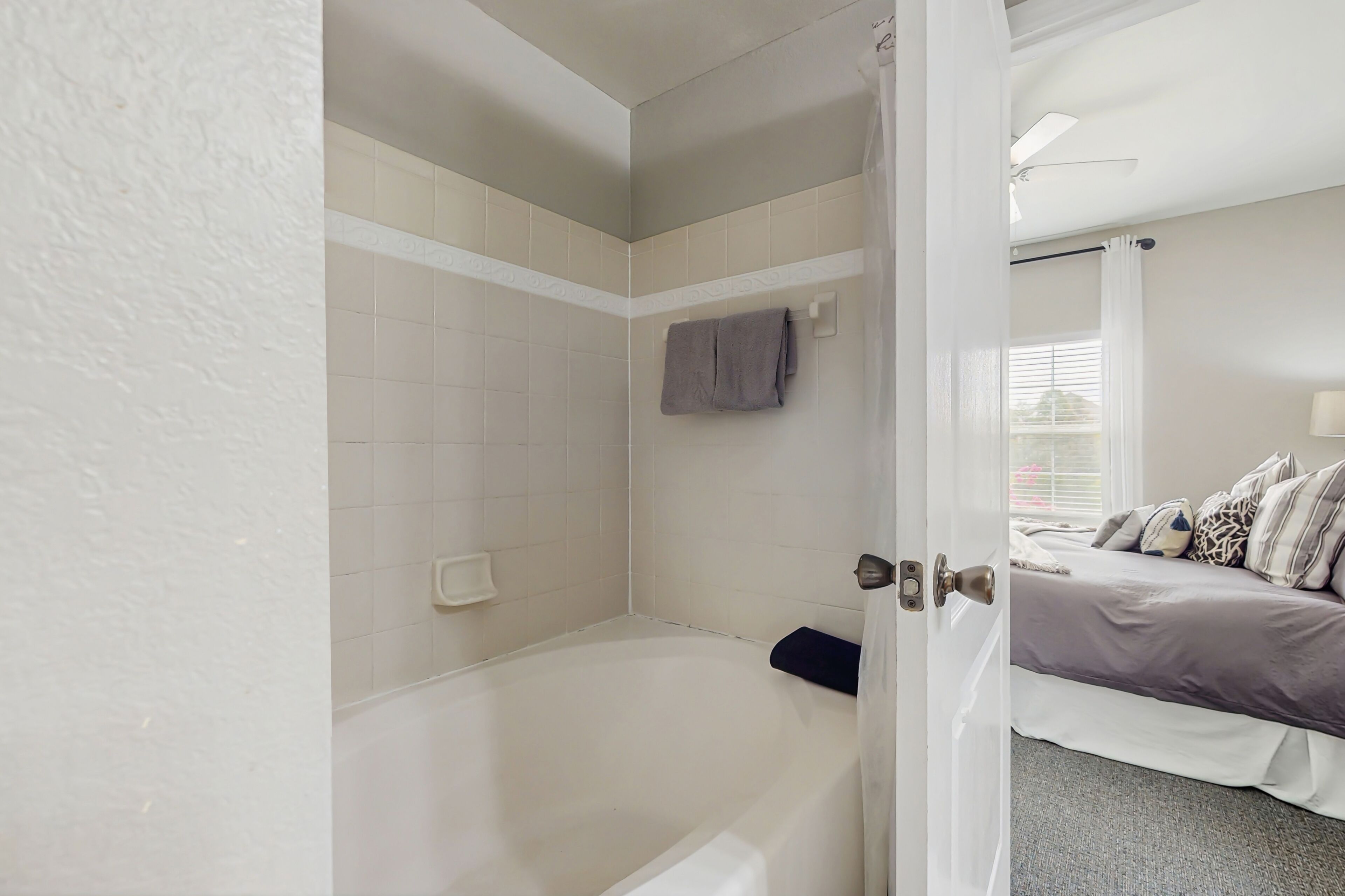 A bathroom with a bathtub, a towel rack, and a shower area.