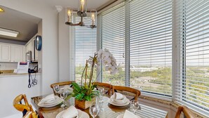 A dining area with a table set for four, a potted plant, and a view through large windows. - Blue Heron Beach I (Orlando)