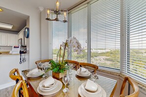 A dining area with a table set for four, a potted plant, and a view through large windows. - Blue Heron Beach I (Orlando)