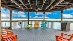 A covered deck with wooden beams, a ceiling fan, and three Adirondack chairs. - Blue Heron Beach I (Orlando)