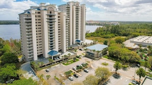A high-rise hotel with multiple floors, a parking area, and a view of a body of water. - Blue Heron Beach I (Orlando)