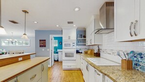 A modern kitchen with white cabinetry, a granite countertop, and a built-in microwave. - Lakefront 4BR Home With Pool, Outdoor Kitchen & Serene Florida Getaway (Lake Placid)
