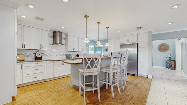 A modern kitchen with white cabinetry, wooden flooring, and pendant lighting. - Lakefront 4BR Home With Pool, Outdoor Kitchen & Serene Florida Getaway (Lake Placid)