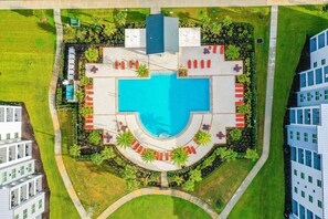Ein Luftbild eines Hotels mit einem zentral gelegenen Schwimmbad, umgeben von Liegebereichen und Grünflächen.