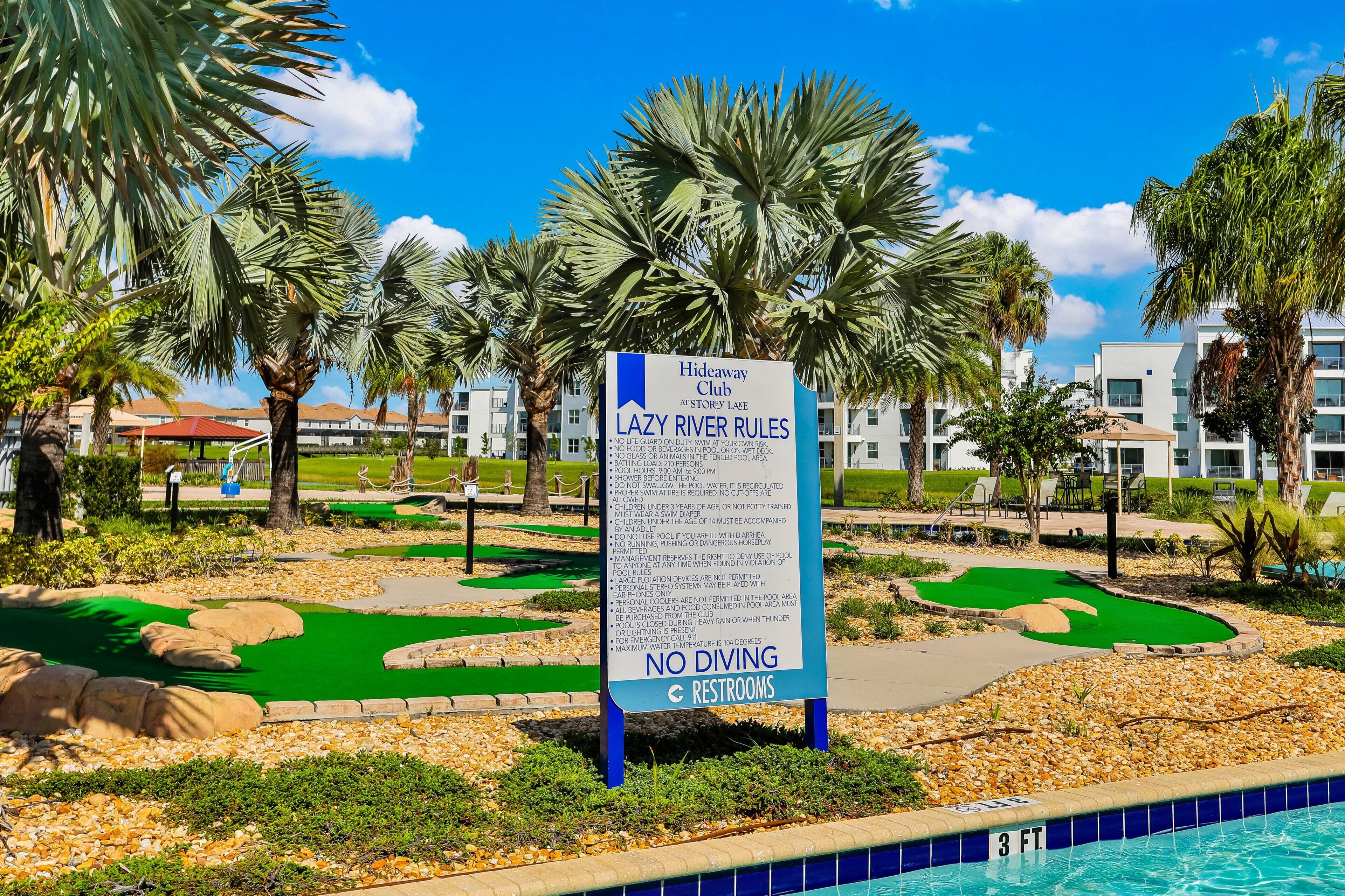A pool area with a sign detailing pool rules, a pool, and a golf course.