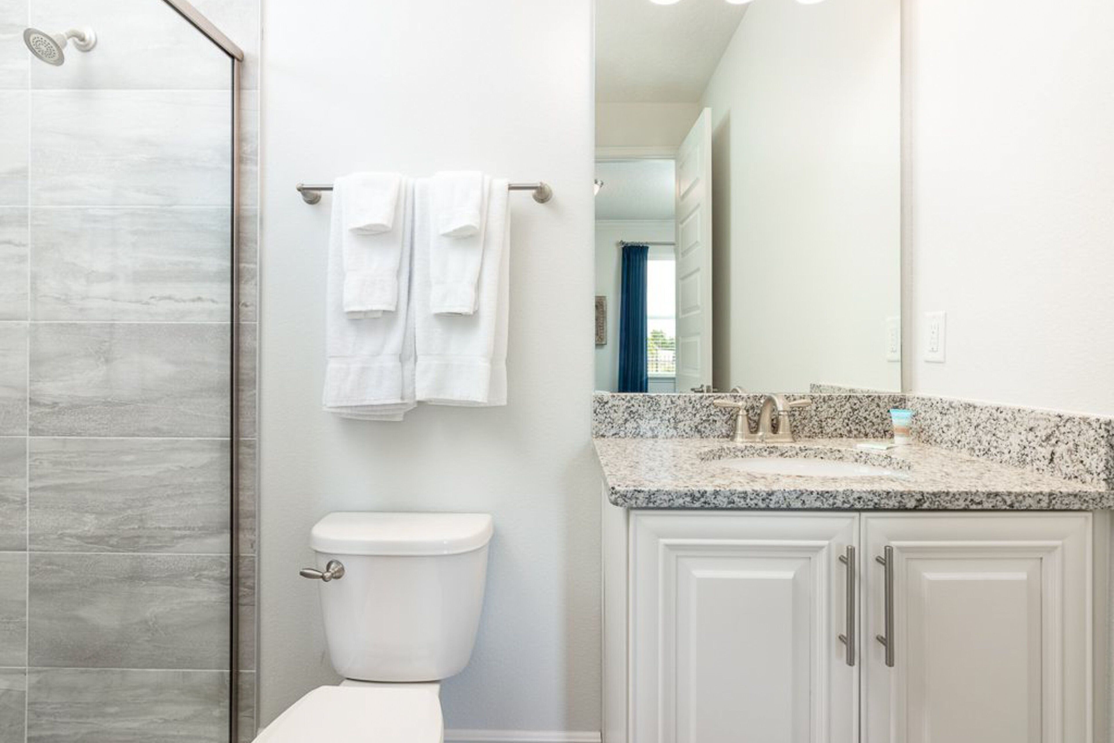 A bathroom with a shower, toilet, and vanity with a mirror.