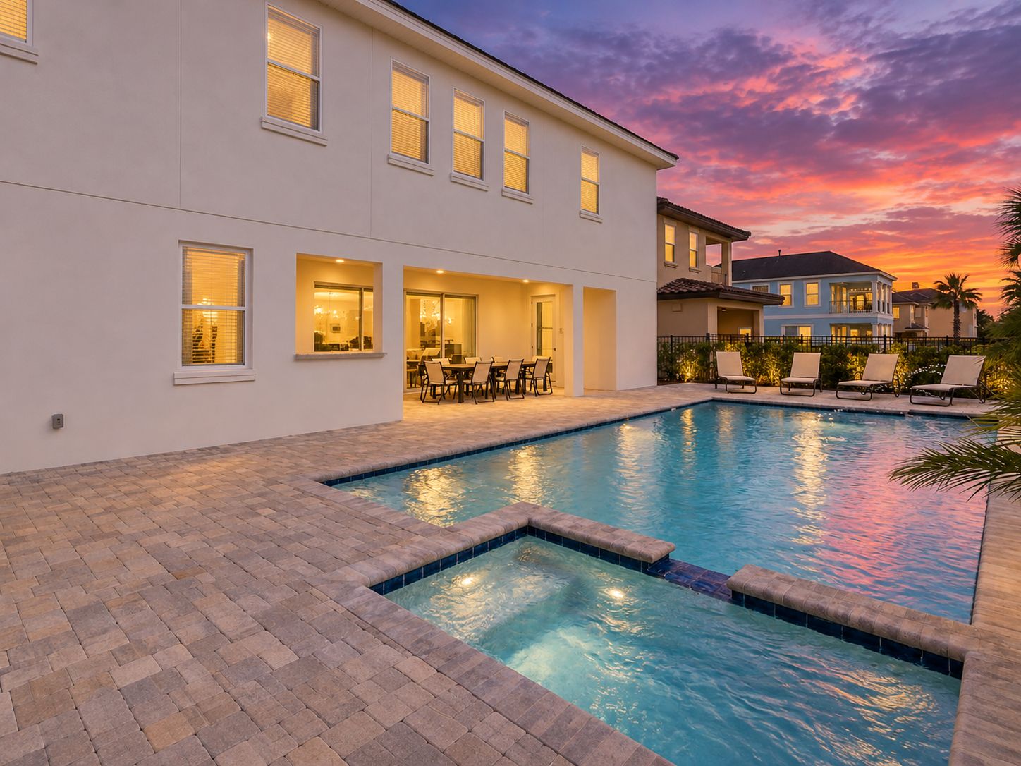 A residential property with a swimming pool, outdoor seating area, and a view of the sunset.