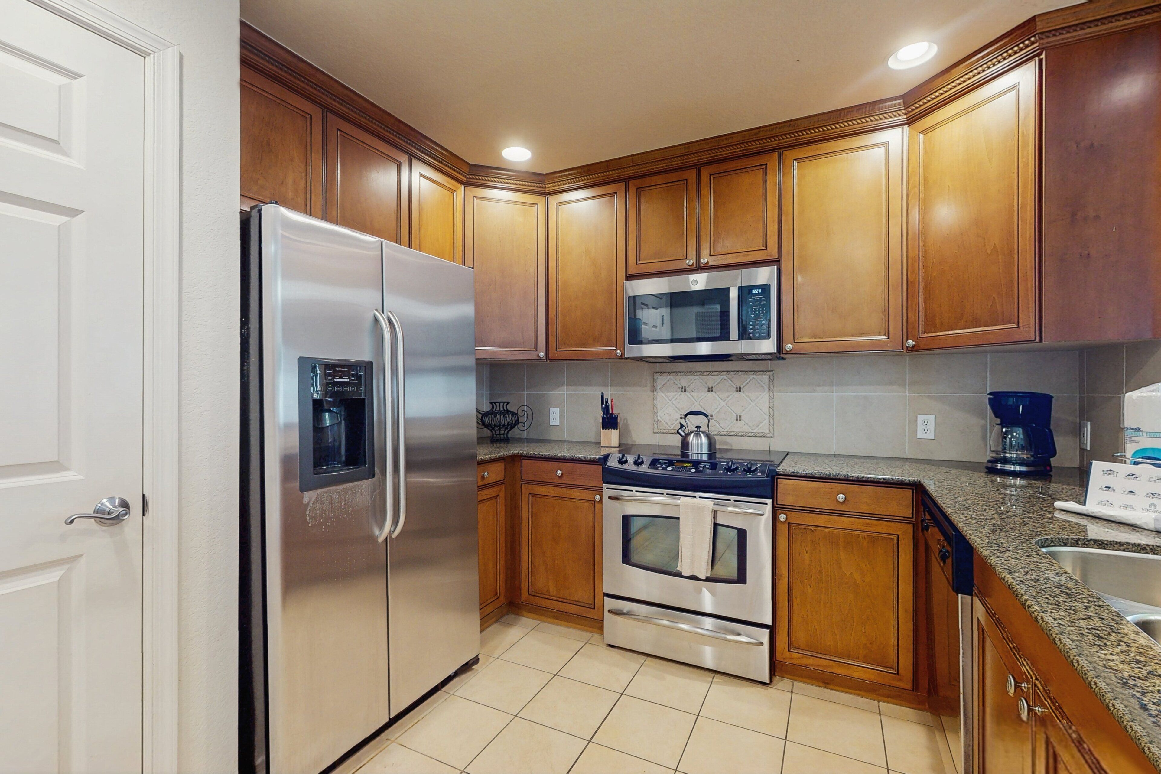 A kitchen with wooden cabinets, stainless steel appliances, and a tiled backsplash.
