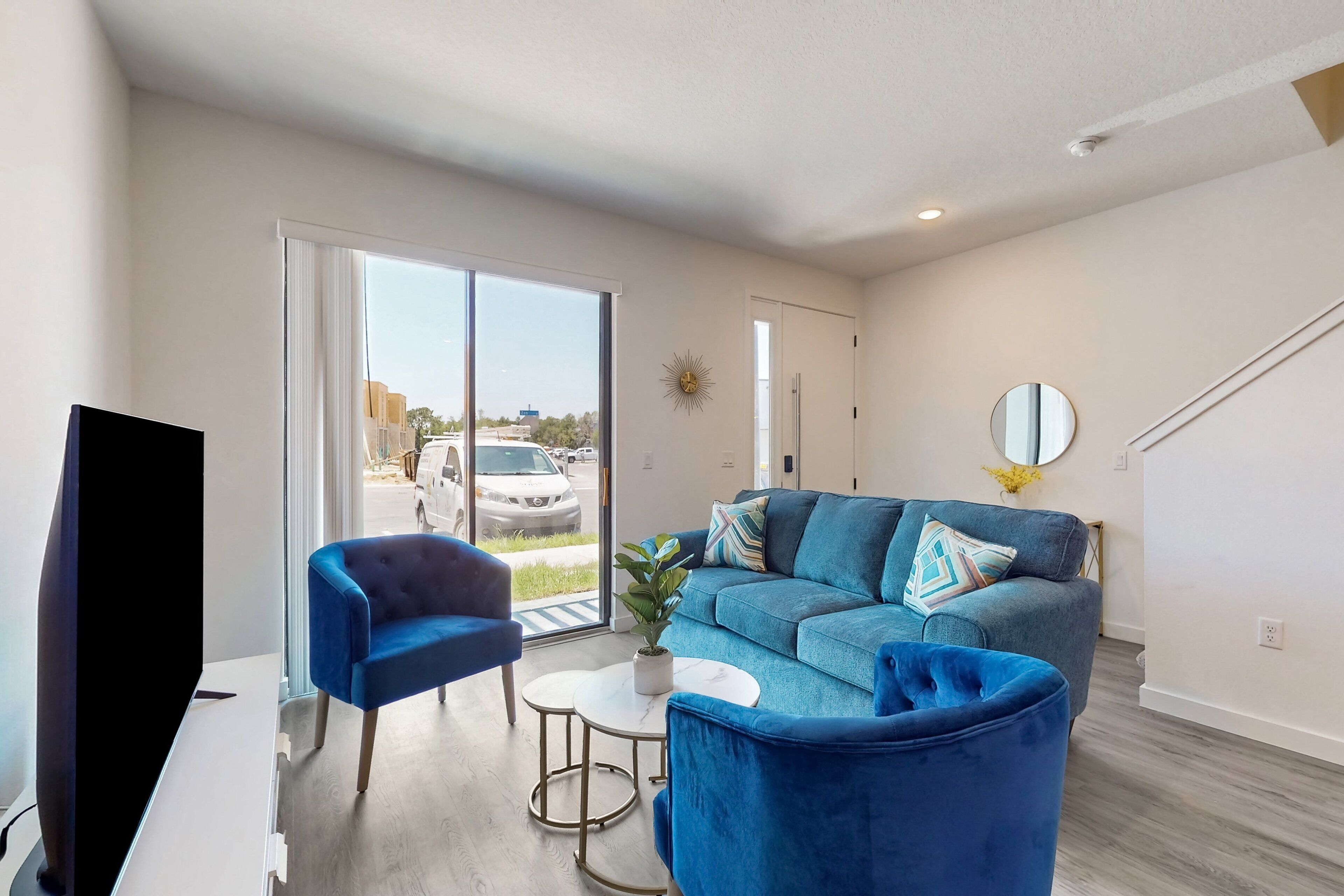 A living room with a blue sofa, a blue armchair, a TV, and a small table with a plant.