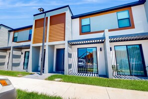 Un edificio residencial moderno de varios pisos con grandes ventanales, techo plano y césped bien cuidado.