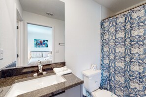 Un baño con lavamanos, inodoro y cortina de ducha.