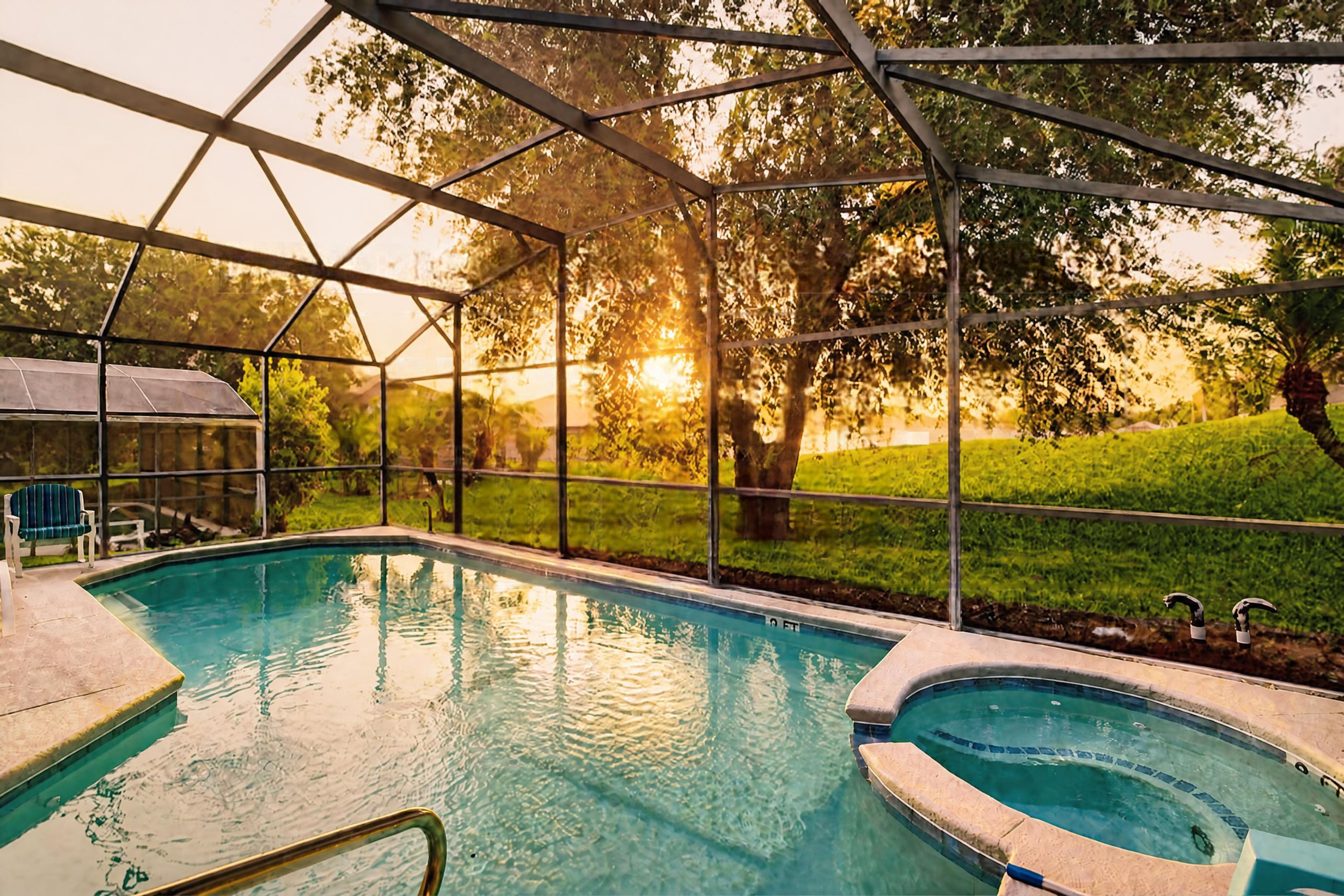 Una piscina con cerramiento de vidrio, rodeada de árboles y césped.