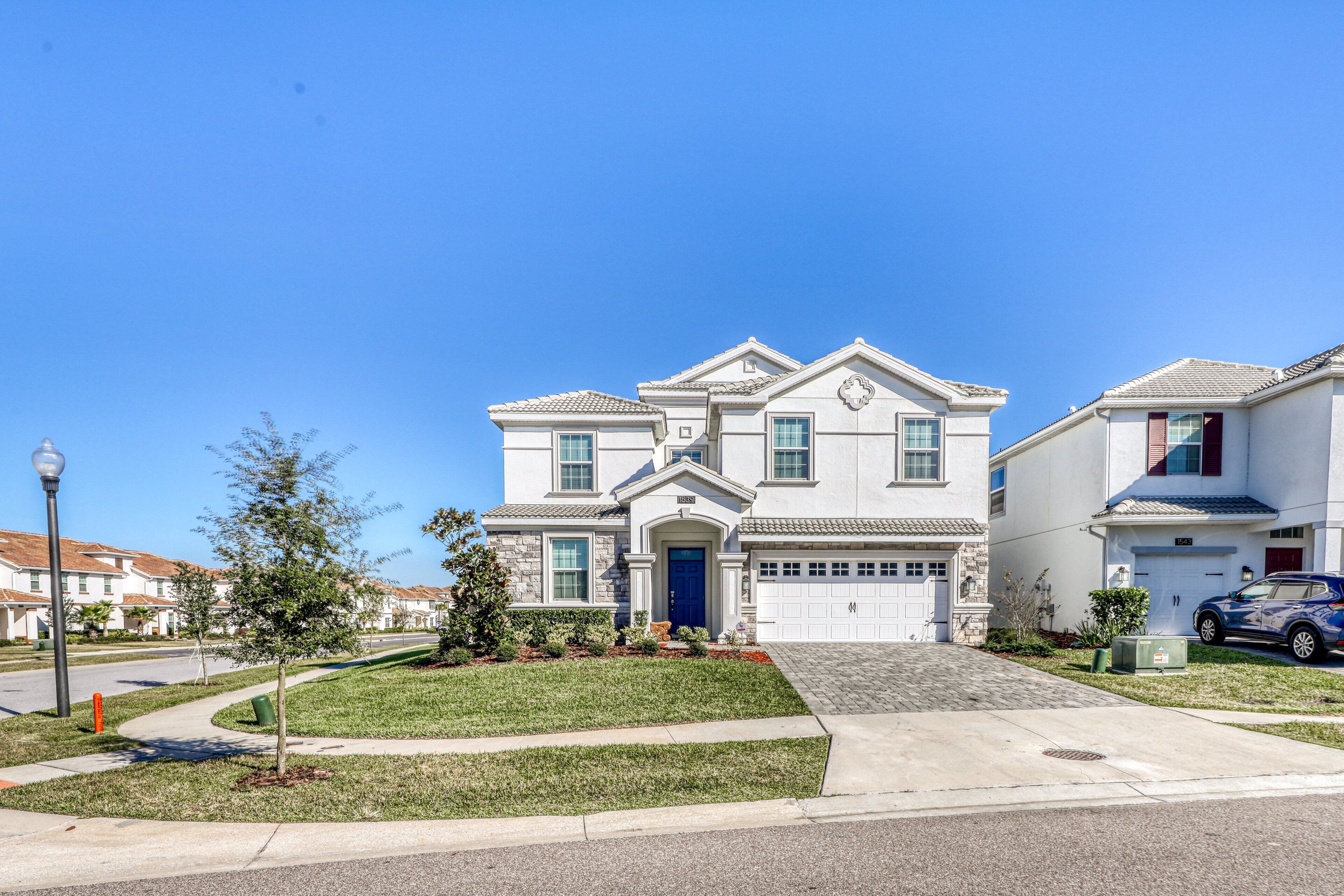 A two-story residential building with a front garage, a driveway, and a well-maintained lawn.