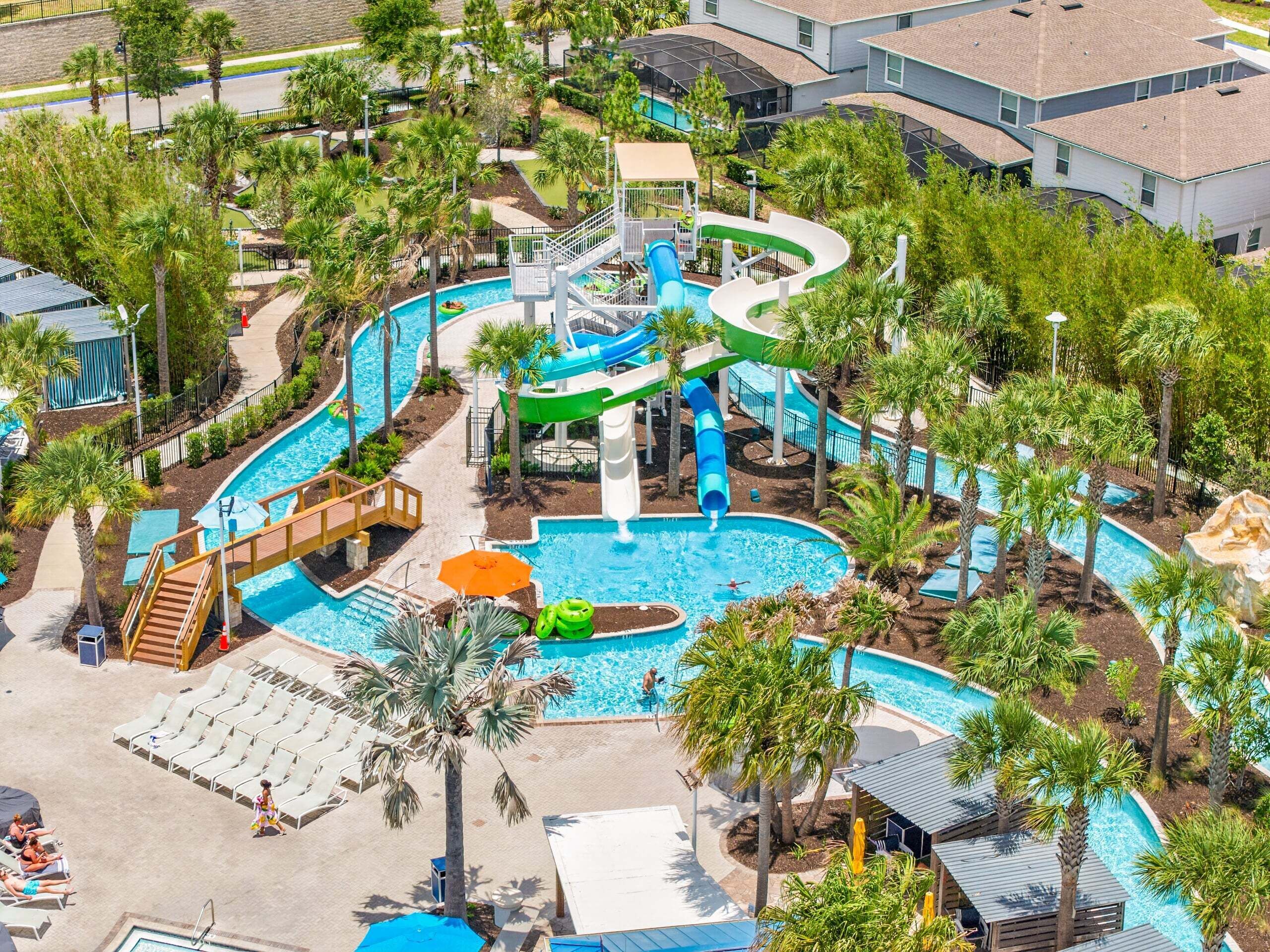 Ein Wasserpark mit mehreren Rutschen, einem Pool und Liegebereichen, umgeben von Palmen.