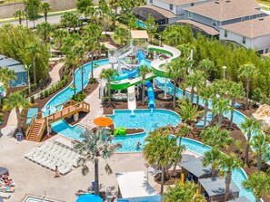 Een waterpark met meerdere glijbanen, een zwembad en ontspanningszones, omringd door palmbomen.