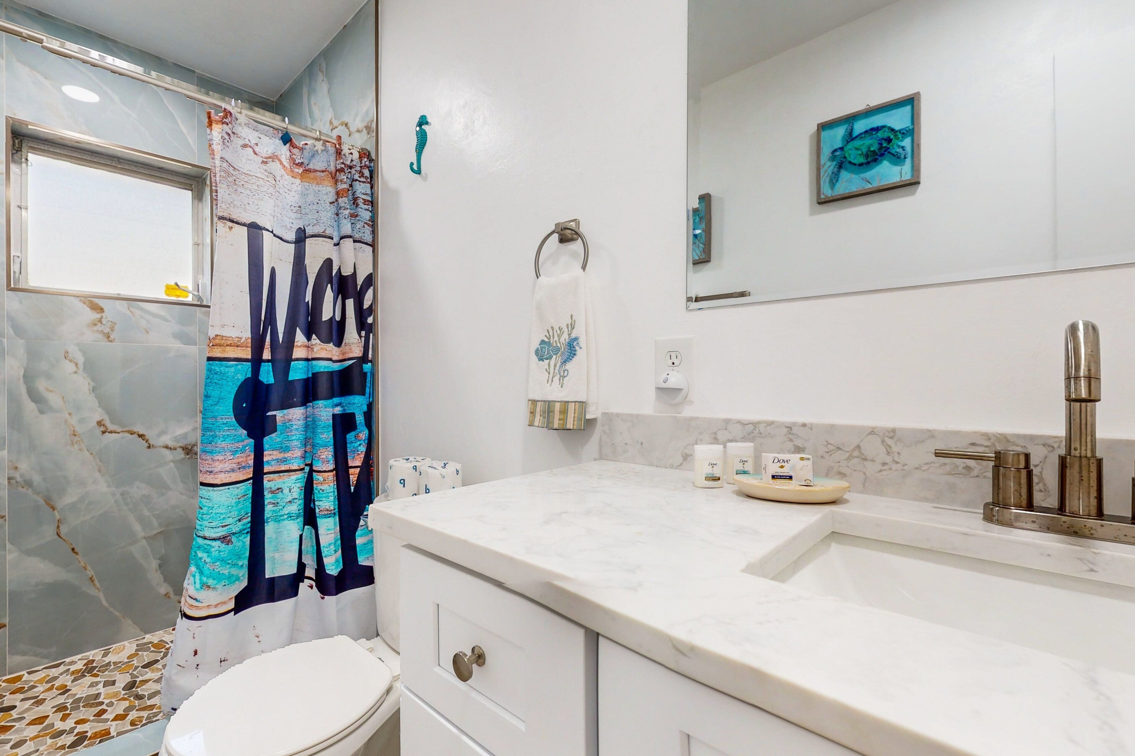 Une salle de bain avec un rideau de douche, des toilettes, un lavabo doté d’un robinet moderne et un miroir.