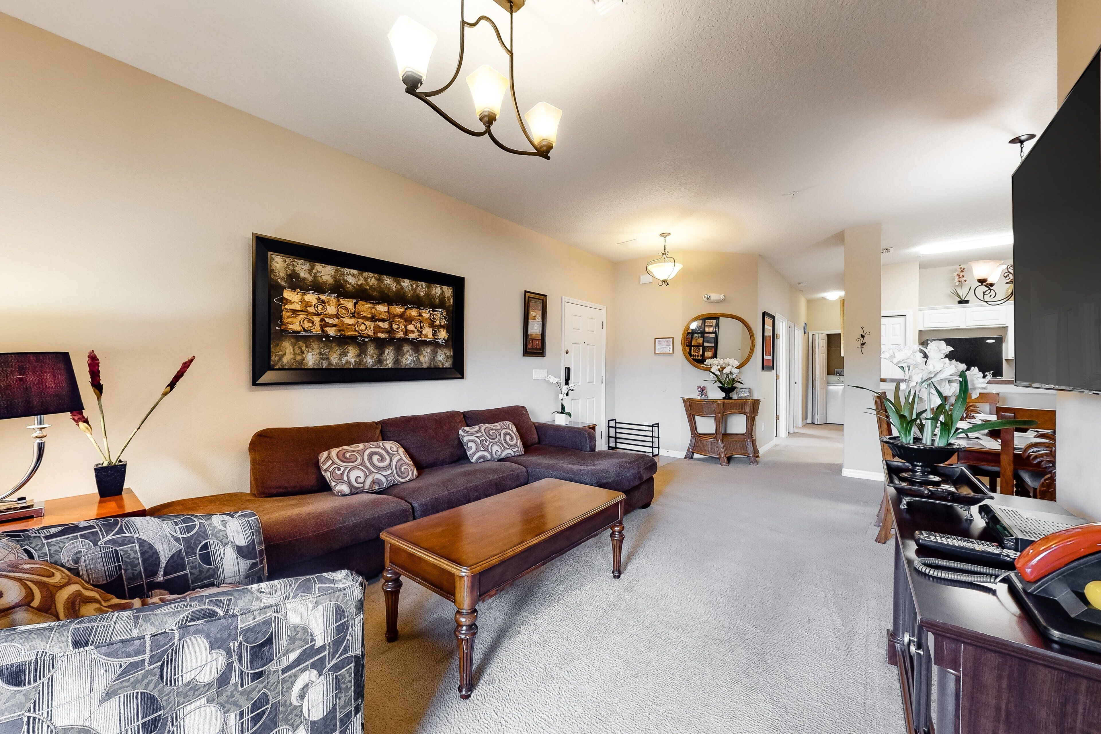 A living room with a sofa, coffee table, patterned armchair, and a painting on the wall.