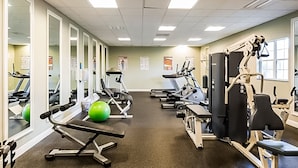 Ein Fitnessstudio mit Trainingsgeräten, Spiegeln und einem grünen Übungsball.