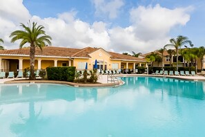 A swimming pool with lounge chairs and palm trees, surrounded by yellow buildings. - Family Home W/shared Pool,wifi,ac,lake Views - Close to Walt Disney World Resort (Kissimmee)